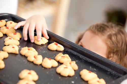 A child swipes a cookie off the baking tray