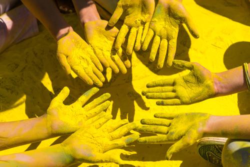 Hände mit gelbem Farbpulver