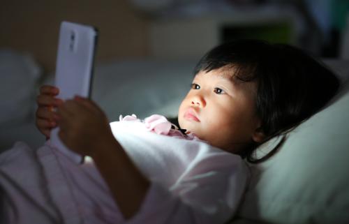 Little girl in bed staring at a smartphone