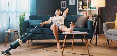 Woman relaxing to music on the sofa while cleaning the floor