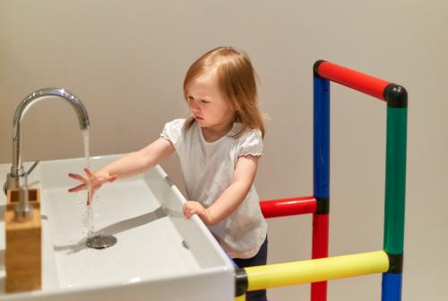 Une petite fille se lave les mains sur une tour d’apprentissage