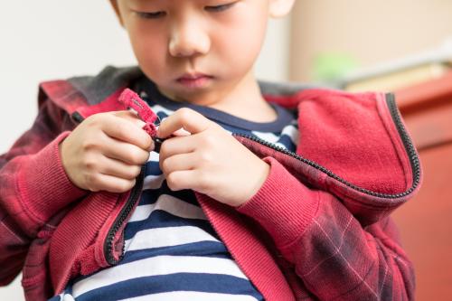 A boy zips up his jacket